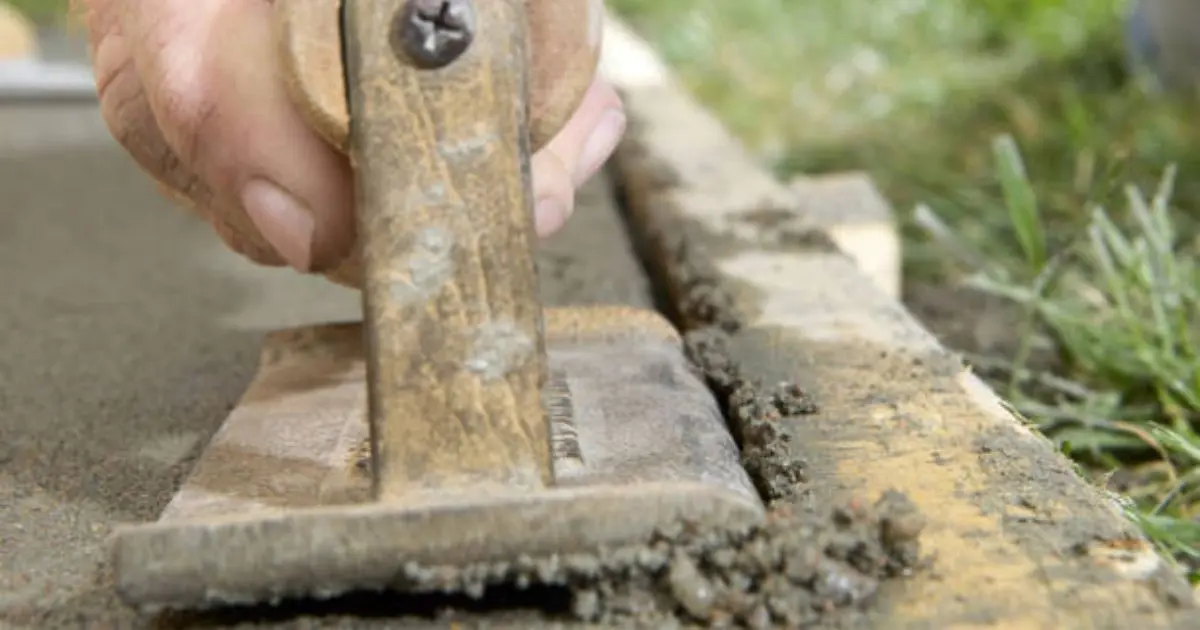 Concrete edging tool creating clean control joint in fresh slab