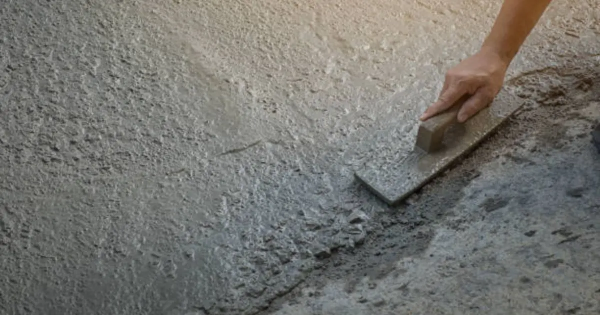 Professional concrete finisher troweling fresh slab to smooth finish