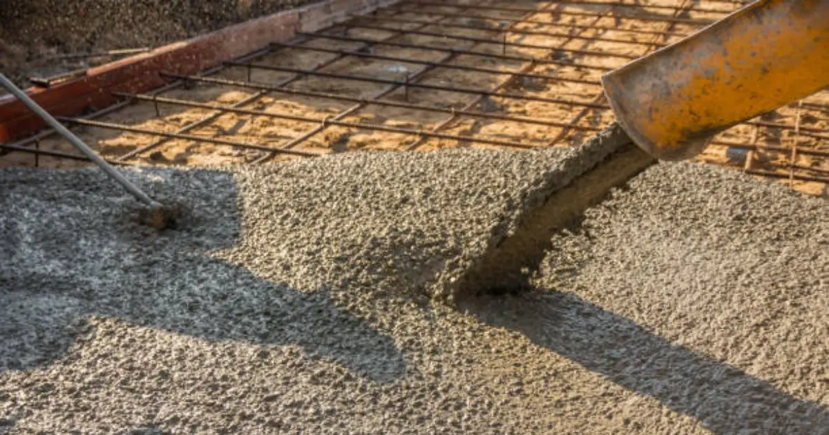 Fresh concrete being poured into rebar-reinforced formwork on job site