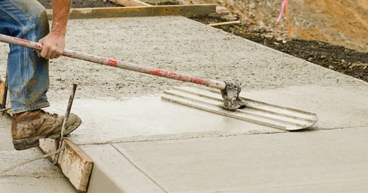 Long-handle bull float being used to level large concrete pour