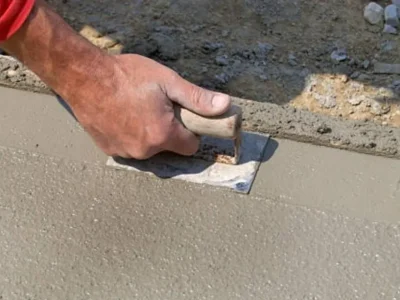 Close-up of steel trowel smoothing wet concrete to polished surface